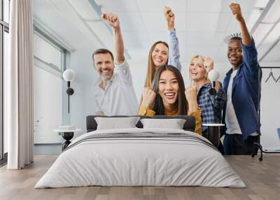 Portrait of diverse group of colleagues cheering together in office Wall mural