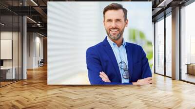 Portrait of handsome confident middle-aged business executive looking at camera smiling with arms crossed outside Wall mural