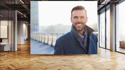 Portrait of happy businessman standing outdoors during sunny winter day Wall mural