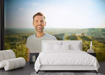 Portrait of man smiling at camera while on trip in the mountains Wall mural