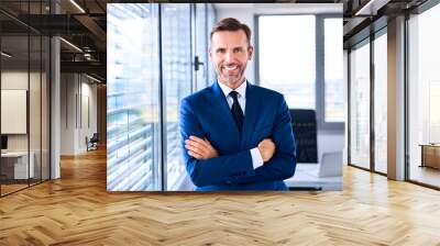 Portrait of successful businessman standing in corner office Wall mural