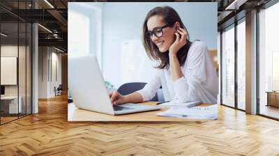 Portrait of veautiful cheerful young businesswoman working on laptop and laughing in home office Wall mural