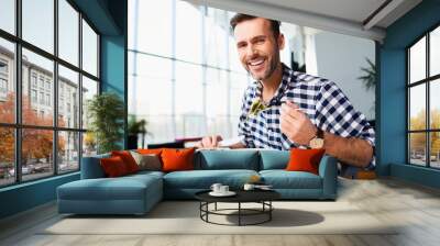 Smiling man eating in cafe Wall mural