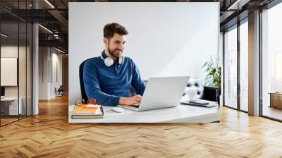 Smiling young man working on laptop Wall mural