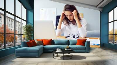 Stressed young woman sitting at desk working from home office Wall mural