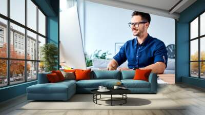 Successful young man working on computer from home Wall mural