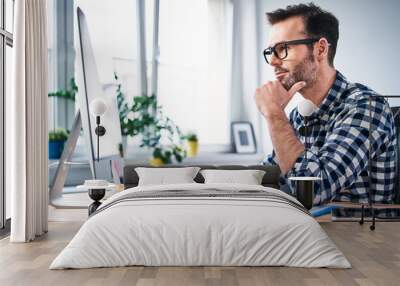 Thoughtful freelancer looking at computer while working from home office Wall mural