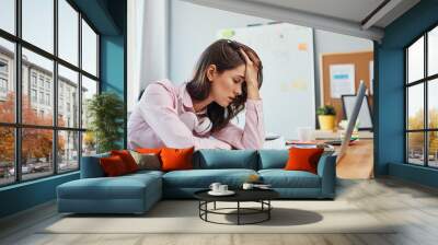 Tired young woman in office having headache working on project Wall mural