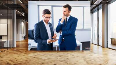 Two businessmen looking at tablet and discussing financial matters in the office Wall mural