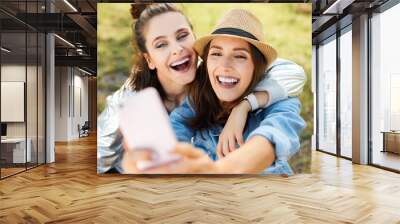 Two young women having fun taking selfie outdoors Wall mural