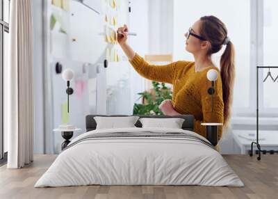 Young businesswoman planning on whiteboard in startup office Wall mural