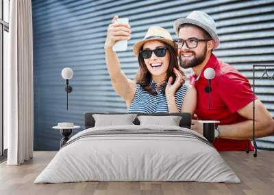 Young couple smiling and taking selfie outdoors Wall mural