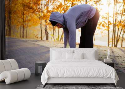 Young runner stretching before winter run Wall mural