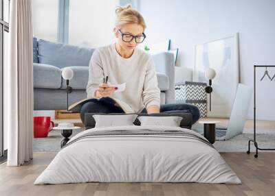 Young woman looking at bills while sitting on floor managing home budget Wall mural