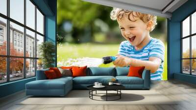 little boy playing and cooling off with a garden water hose, summer fun Wall mural