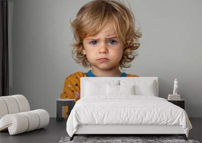 Angry little boy standing with his arms crossed. Wall mural