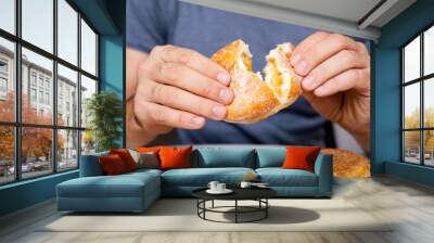 Man eating doughnut with apricot jelly. Czech Donut in hands closeup. Wall mural