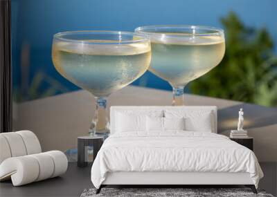 Cold sparkling wine, cava or champagne in two coupe glasses on table with blue sea water view Wall mural