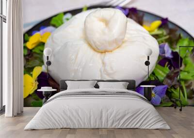 Fresh handmade soft Italian cheese from Puglia, white ball of burrata foglia saporosa or burratina cheese made from mozzarella and cream filling served with green rocket salad witn viola flowers Wall mural