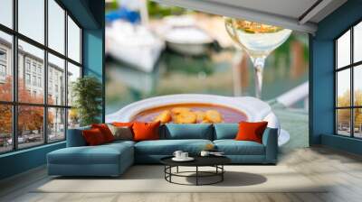 Homemade tasty fish or bisque soup with croutons served with glass of cold white wine and view on yacht boats and houses of Port Grimaud, French Riviera, France. Food of Provence Wall mural