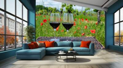 Picnic on old vineyard with red poppies flowers and green grass with glasses of red Cahors wine, summer in Cahors wine making region in France, weekend background Wall mural