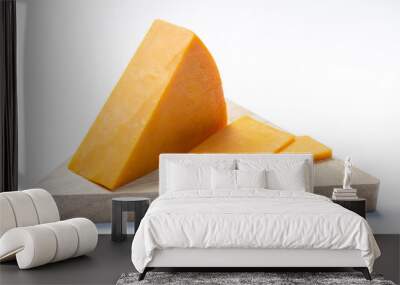 Piece of hard orange Cheddar cheese on wooden cheese plank isolated close up Wall mural