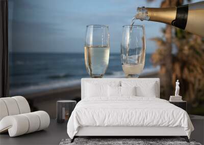 Pouring of Spanish cava sparkling wine is glasses with view on blue sea and sandy beach, Costa del Sol vacation destination, Andalusia, Spain Wall mural