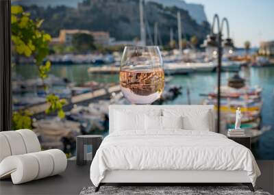 Rose wine in glass served on outdoor terrace with view on old fisherman's harbour with colourful boats in Cassis, Provence, France Wall mural