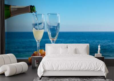 Waiter pouring Champagne, prosecco or cava in two glasses on outside terrace with sea view Wall mural