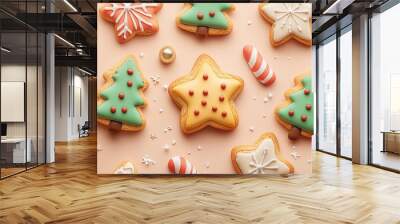 An array of holiday-themed cookies with green Christmas trees, white snowflakes, and star-shaped cookies decorated in vibrant colors laid on a soft peach background. Wall mural