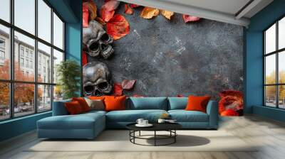 This image showcases two skulls surrounded by vibrant autumn leaves on a dark textured surface, creating a striking and mysterious contrast that evokes curiosity and intrigue. Wall mural