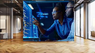 Two black man and woman software engineers in office collaborating in software development writing code at desk programming at laptop Wall mural