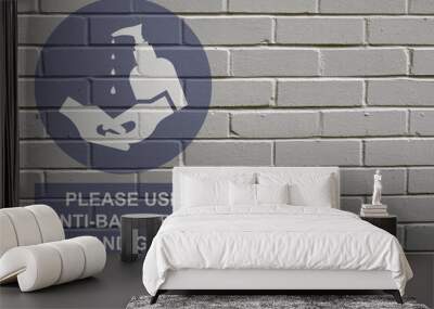 White decayed faded brick wall background with please use anti bacterial hand gel sign to stop the spread of the worldwide pandemic Wall mural