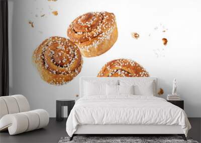 Fresh baked cinnamon buns with crumbs flying falling isolated on white background. Wall mural