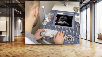 Portrait of young male technician operating ultrasound machine Wall mural