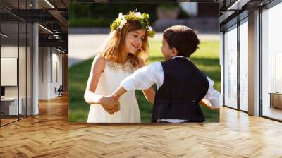 A girl in a white dress is dancing with a boy in a fashionable suit. Wall mural