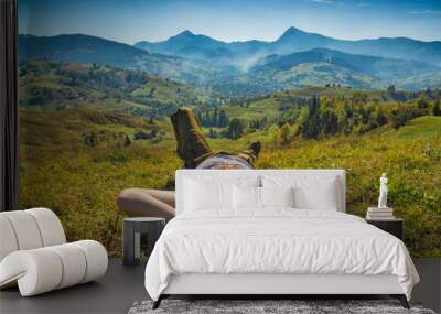 Tourist lying on a meadow in a grass and enjoy the sunlight Wall mural