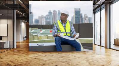 African male civil engineer inspects a commercial building construction site in a real estate project. Wall mural