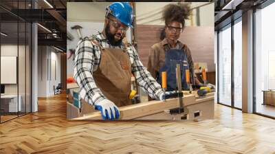 Male carpenter training with woman to work in a woodworking workshop. Carpenter, Handcraft, Industrial, Factory and Engineer concept. Wall mural