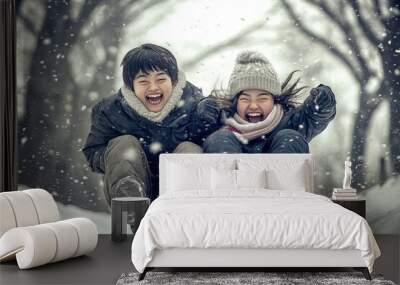 Joyful siblings experiencing the thrill of winter snow on a sleigh ride in a snowy park surrounded by trees during a beautiful snowstorm Wall mural