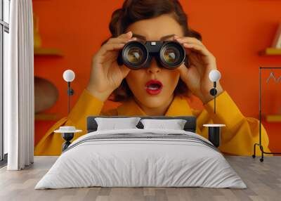 Woman looking into binoculars Looks excited or shocked on an orange background Wall mural