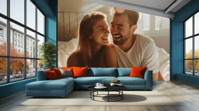 Young couple hugging, teasing and laughing on a white bed. Showing happiness in the morning There was light from the light shining in. Wall mural