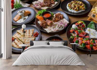 Assorted foodset on table. Kebab of pork, salmon grill, borscht, greek salad, rack of labm, fried potatoes with mushrooms. Wall mural