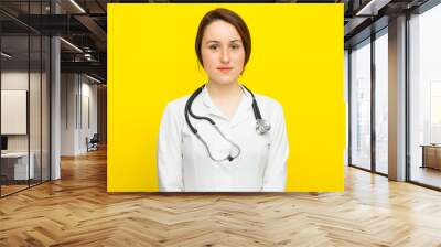 Young female doctor with a stethoscope on yellow background Wall mural