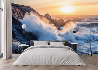 A dramatic sunset over a rocky coastline with large waves crashing against the shore. Wall mural