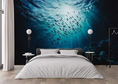 A school of fish swimming in the blue ocean water, with sunlight shining through the surface. Wall mural