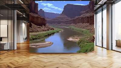 A winding river flows through a canyon, surrounded by red rock cliffs and green vegetation. Wall mural