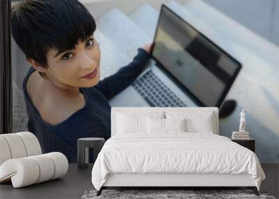 Young woman using laptop - looking up Wall mural