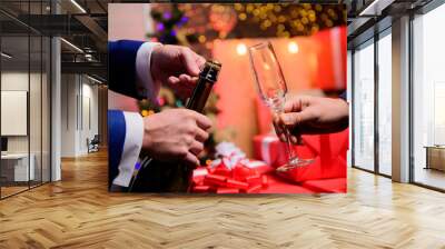 Drink champagne or sparkling wine. Celebrate new year with champagne. Last minute before new year. New year countdown. Hands opening champagne bottle and hold glass christmas decorations background Wall mural