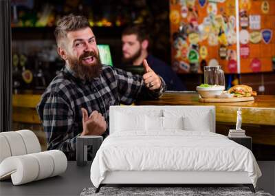 Enjoy meal in pub. High calorie snack. Hipster relaxing at pub. Pub is relaxing place to have drink and relax. Brutal hipster bearded man sit at bar counter. Man with beard drink beer eat burger menu Wall mural